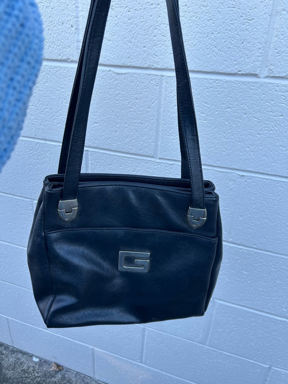 vintage black leather shoulder bag featuring a prominent silver G emblem
